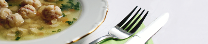 ein Teller mit Suppe, daneben Messer und Gabel